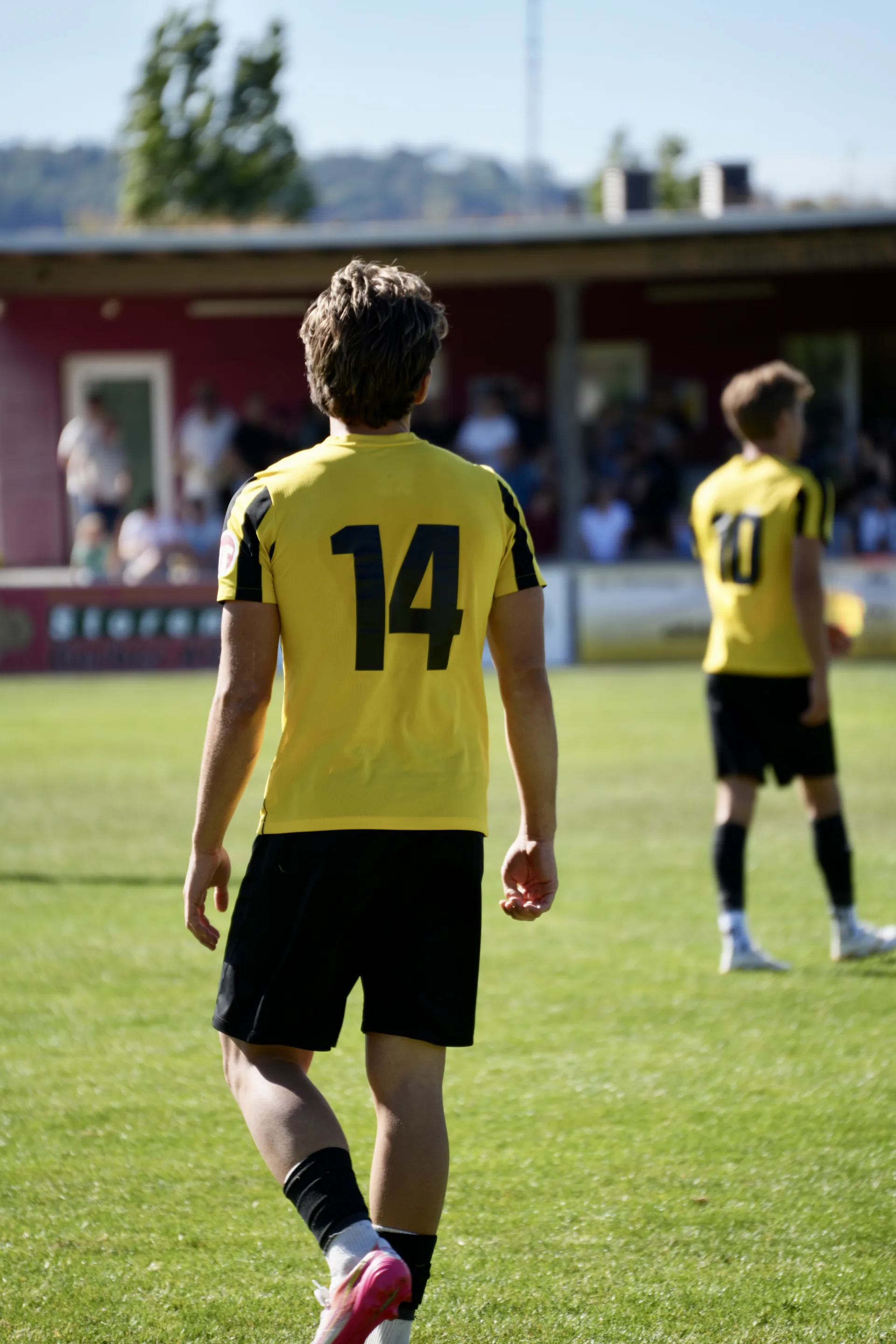 Spieler mit der Rückennummer 14 auf dem Platz, im Hintergrund die Tribüne