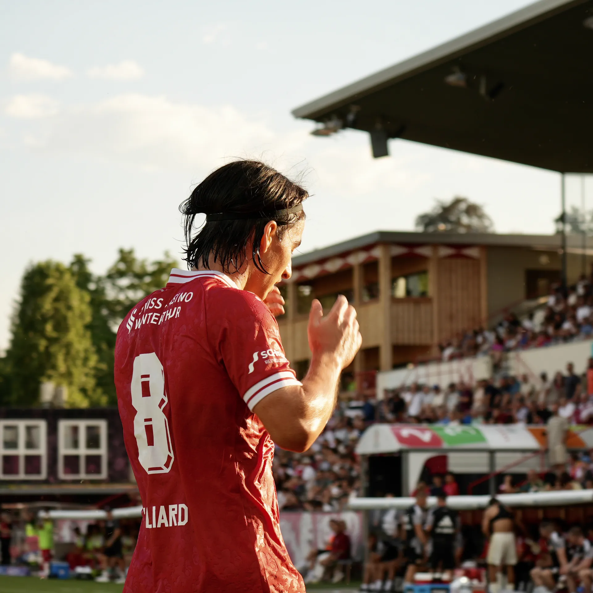 Spieler applaudiert im Abendlicht zur Tribüne
